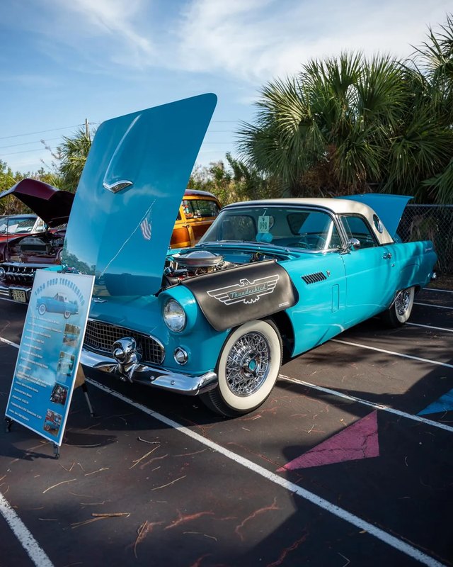 Turquoise classic car with its hood open parked at the Tom Joyce car show.