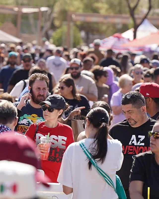 Dense crowd of shoppers walking past market tents at the Desert West Fall Market