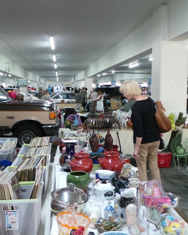 Vendor tables of housewares, records and goods with shoppers browsing at the Pasadena City College Flea Market