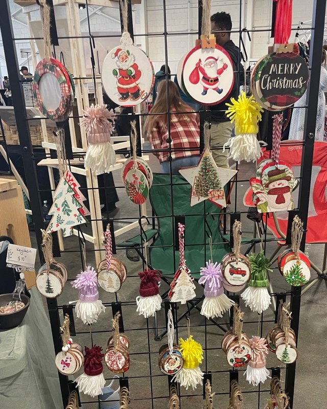 Holiday ornaments and small decorations hanging on a display rack at a market booth.