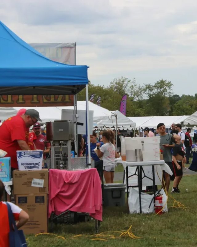 Vendor booths and shoppers on a grassy field at the Warrington Community Day event