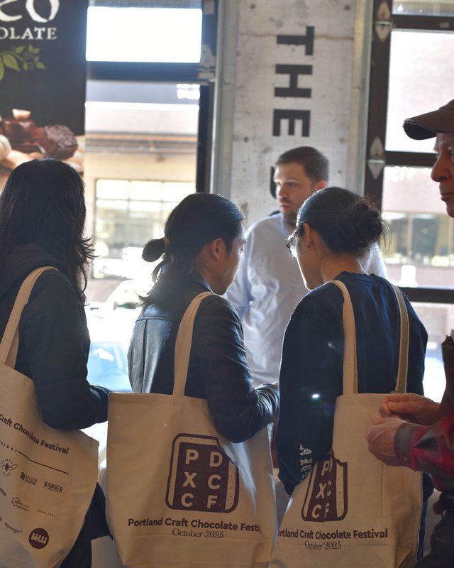Guests with Portland Craft Chocolate Festival tote bags talking at the festival