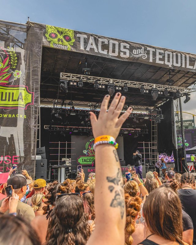 Crowd facing a large stage with a Tacos and Tequila banner at an outdoor festival.