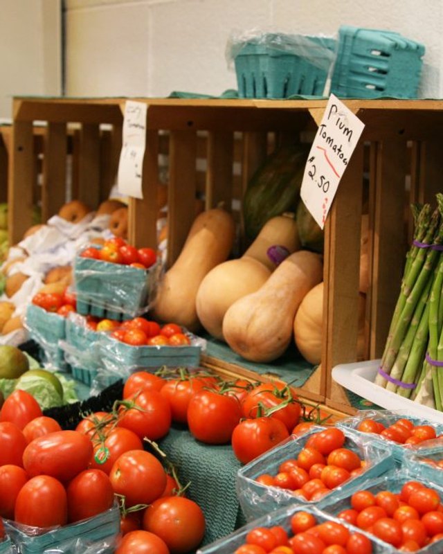 Produce display of tomatoes, apples, squash and asparagus in wooden crates at the Bristol Amish Market