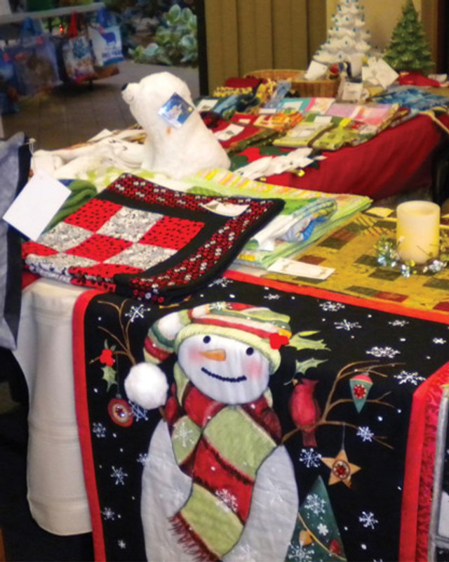 Holiday-themed craft table with snowman and quilted items at a past St. Camillus craft fair.