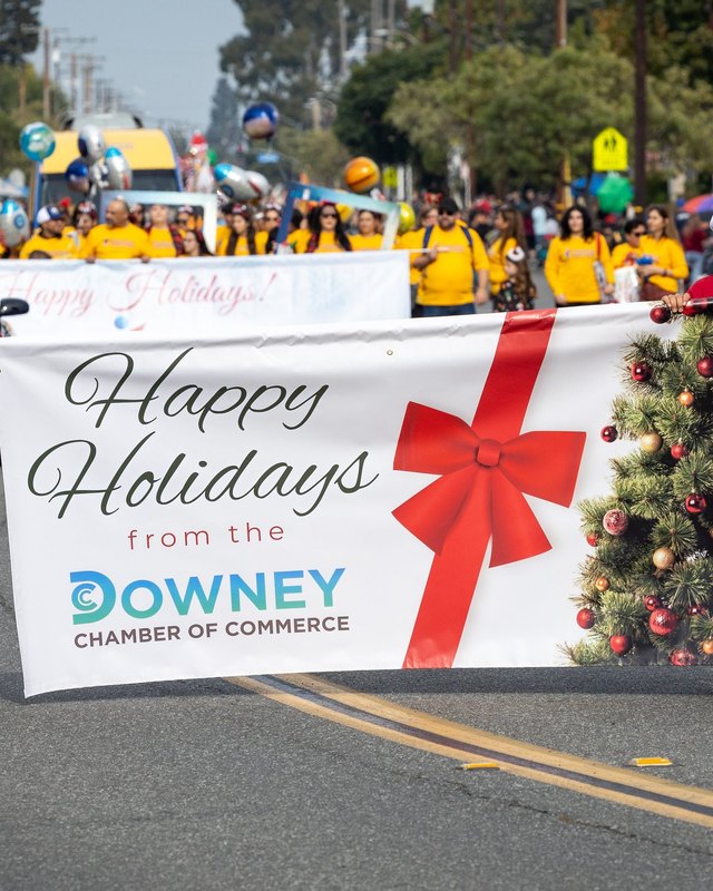 Downey Chamber of Commerce 'Happy Holidays' banner carried by marchers in a holiday parade on a Downey street.