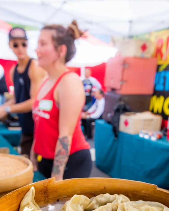 Market visitors and vendors with steamed dumplings in bamboo baskets at a food stall
