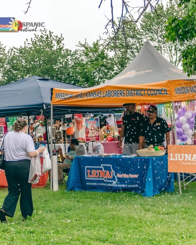 Festival booth tents and vendors with a banner at a park during Fiesta in Florissant