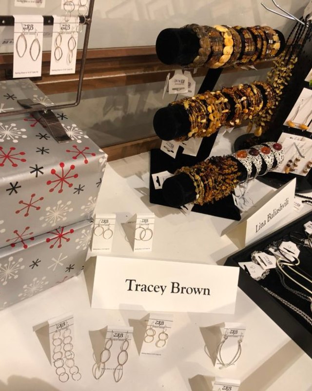 Jewelry and bracelets displayed on a table with a Tracey Brown name card at a craft sale