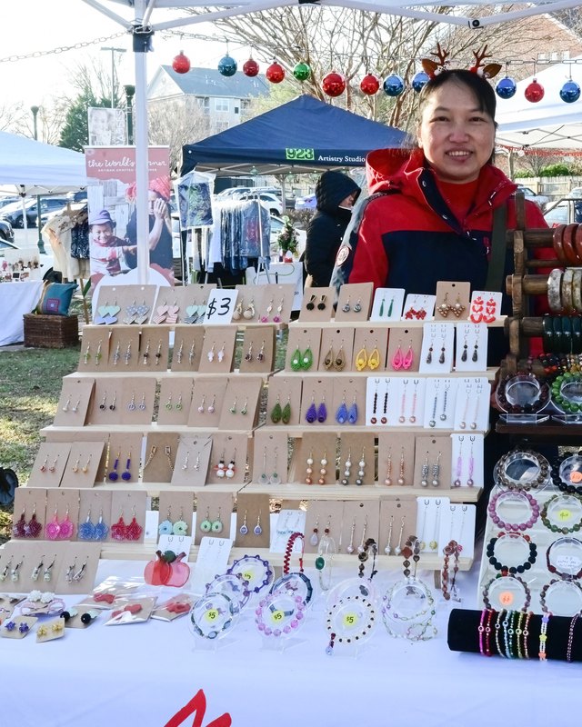 Vendor behind a jewelry and bracelet booth at an outdoor winter market