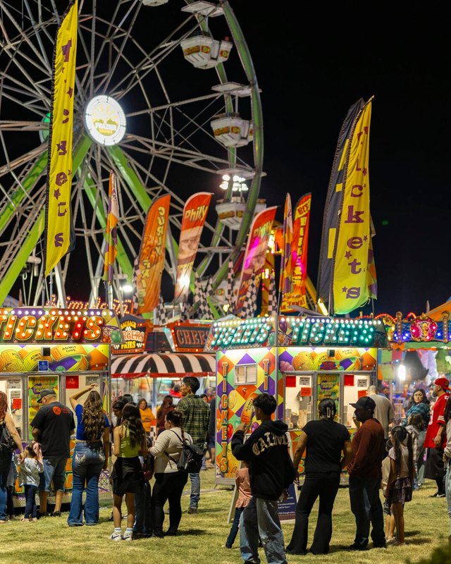 Crowd gathered around a ferris wheel and carnival rides at night during the Billy Moore Days Carnival