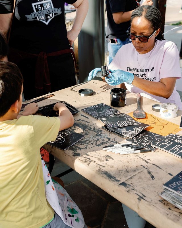 Visitors making prints at a worktable with artists at Art Made Here in Garland