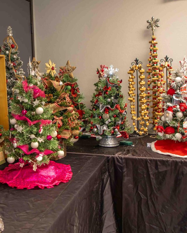 Holiday display of decorated Christmas trees on a vendor table at a boutique