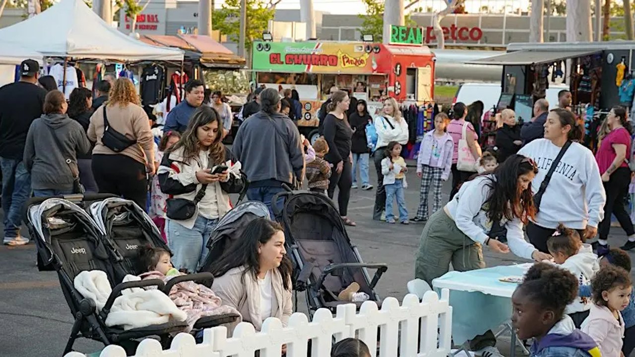 Crowd of shoppers and visitors among market tents along a street-side event.