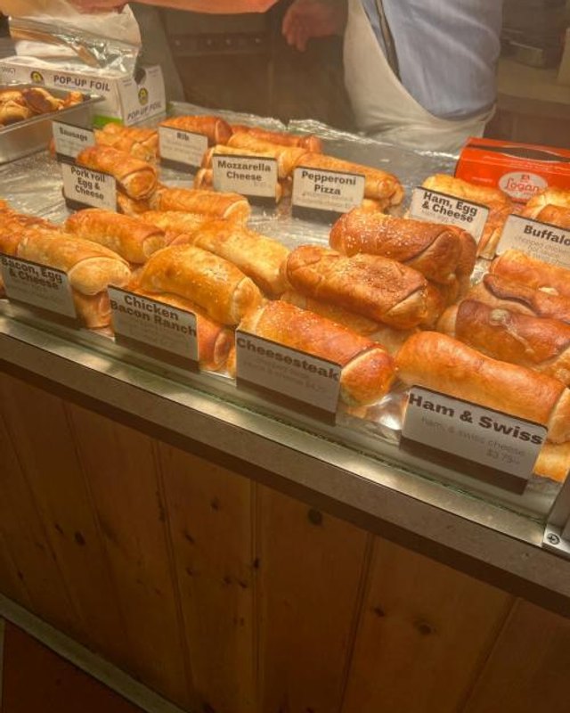 Breads and pastries with handwritten labels displayed at a market counter in Newtown.