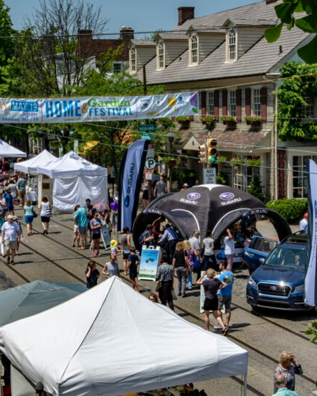 Street crowd and white tents under a Home & Garden Festival banner on Chestnut Hill's main street.