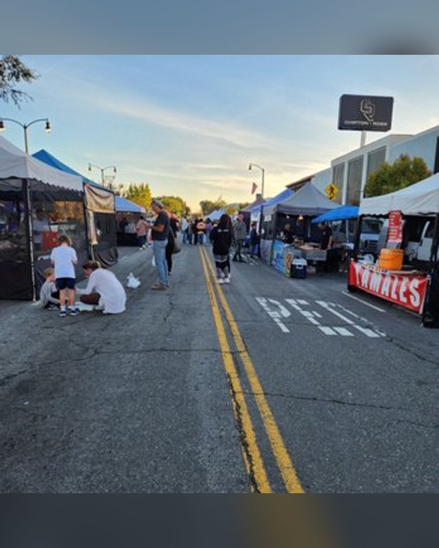 Shoppers walking a street lined with market tents at the El Segundo farmers market