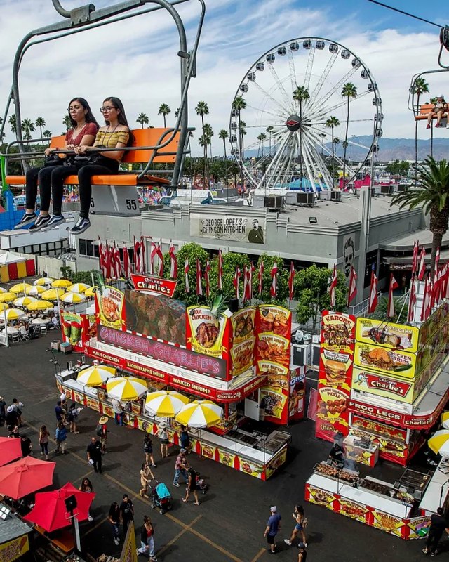 Aerial view of crowds walking past fair food booths and rides at the LA County Fair