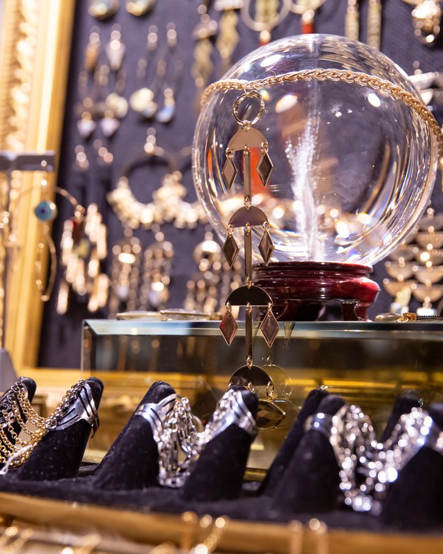 Jewelry displayed on black stands and a gilded tray beside a glass dome at a vendor display