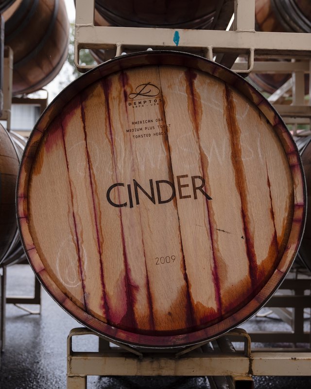 Cinder wine barrels stacked in the winery, one with the Cinder name branded on its head.