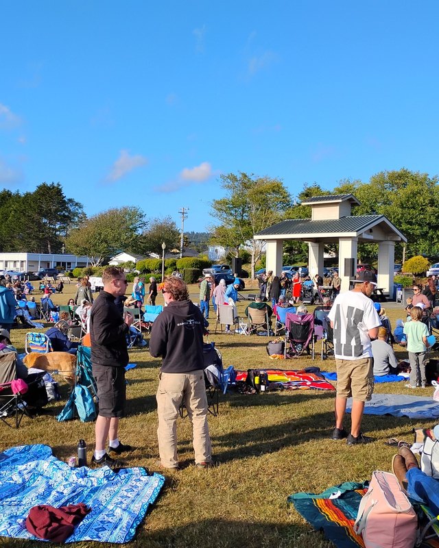 Crowd on the grass at Pierson Park with picnic blankets and a pavilion in the background