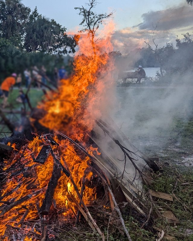 The festival bonfire burning at dusk on the Alva Museum field, with festival-goers watching from the grass.