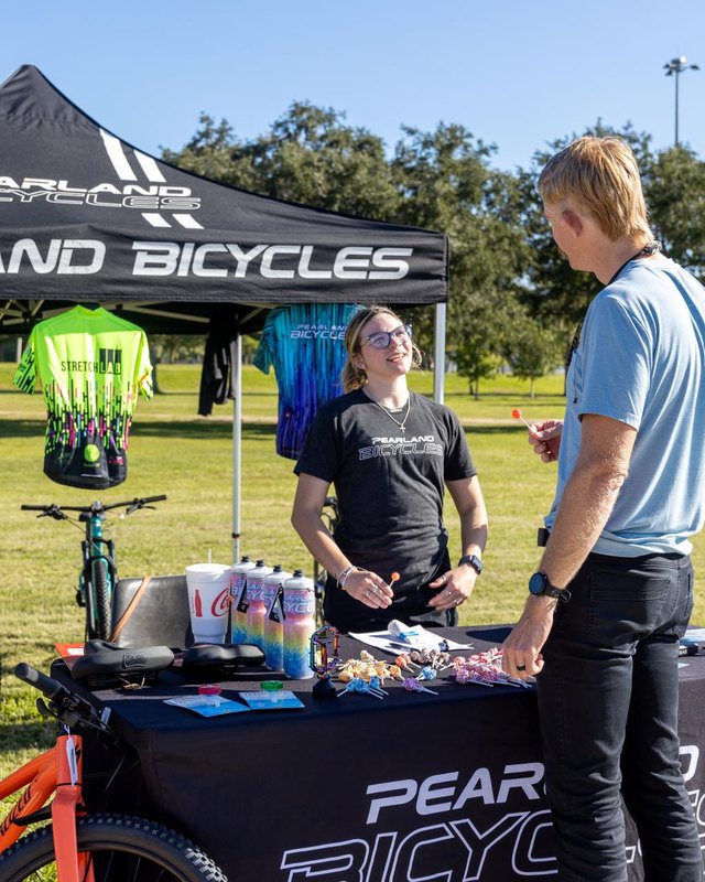 Pearland Bicycles booth with bikes and staff talking to a visitor at Outdoors For All