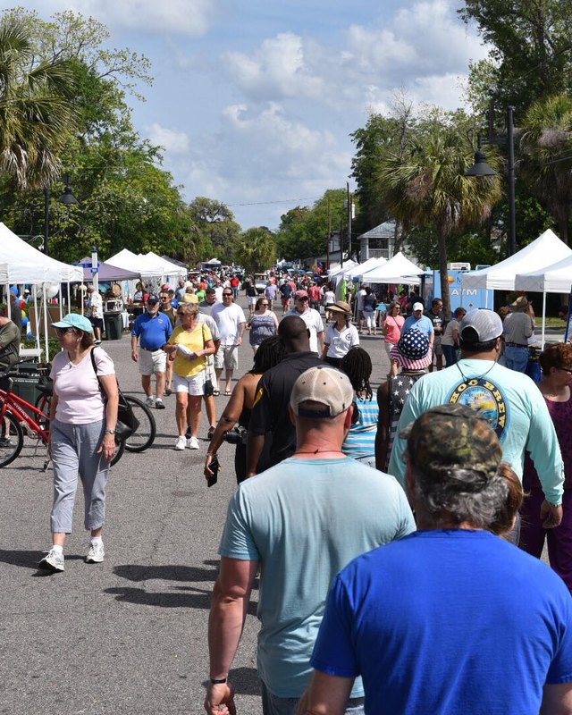 Crowd of shoppers walking past white tent booths at an outdoor street festival in Port Royal.