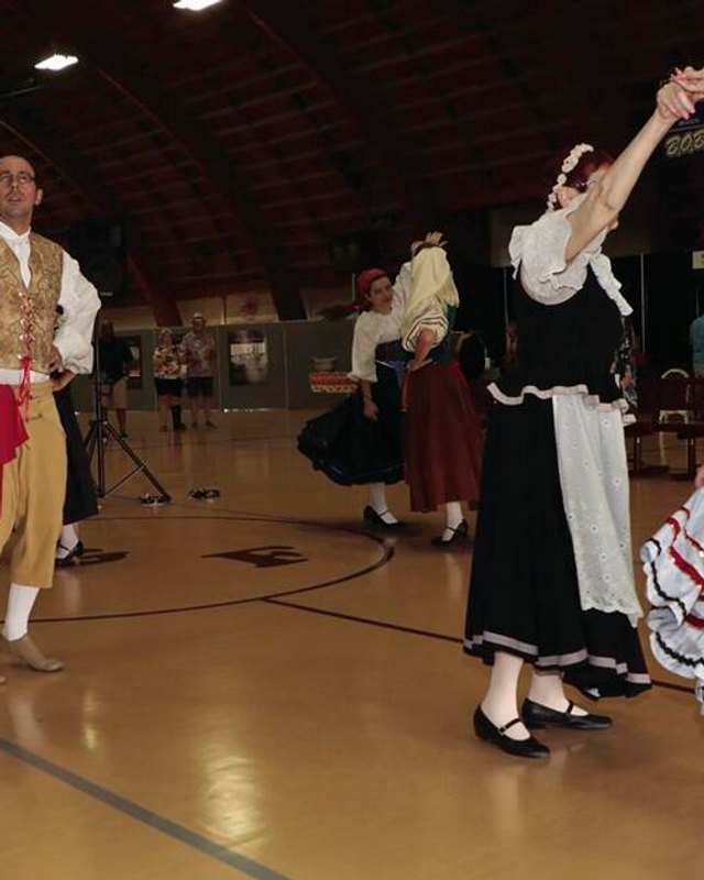 Costumed dancers performing on a gym floor at a Festa Italiana event in Lodi.