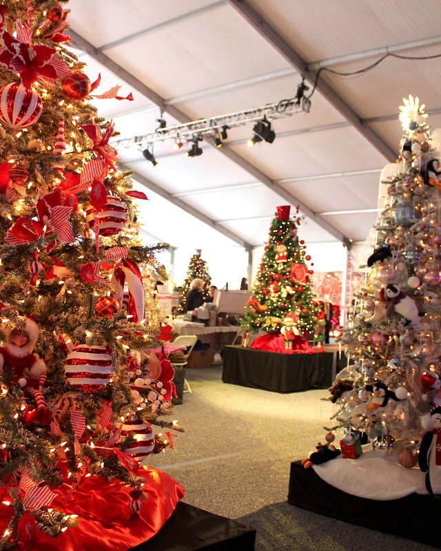 Decorated Christmas trees and displays under a white tent at the Torrance Memorial Holiday Festival
