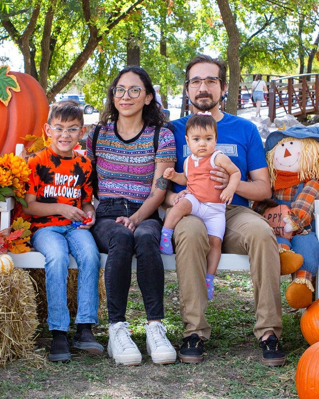 Family posing with pumpkins, hay bales and a scarecrow at Mesquite's PumpkinFest