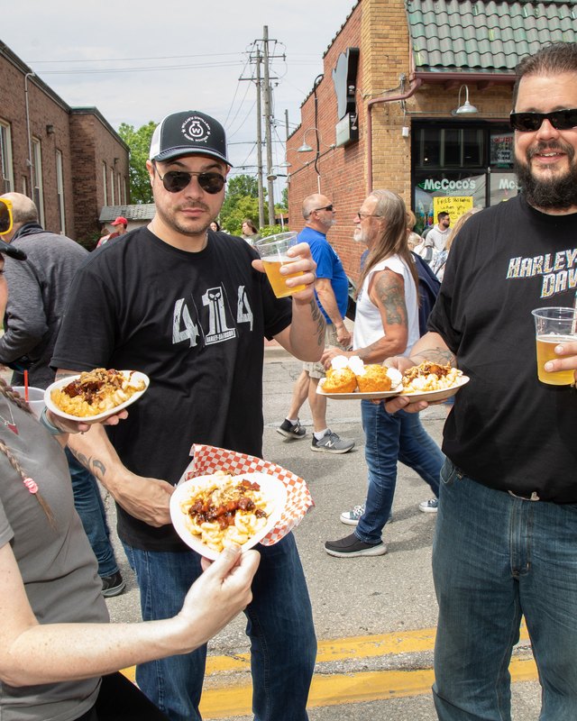 Festival-goers holding food and drinks on a West Allis street during the A La Carte event.