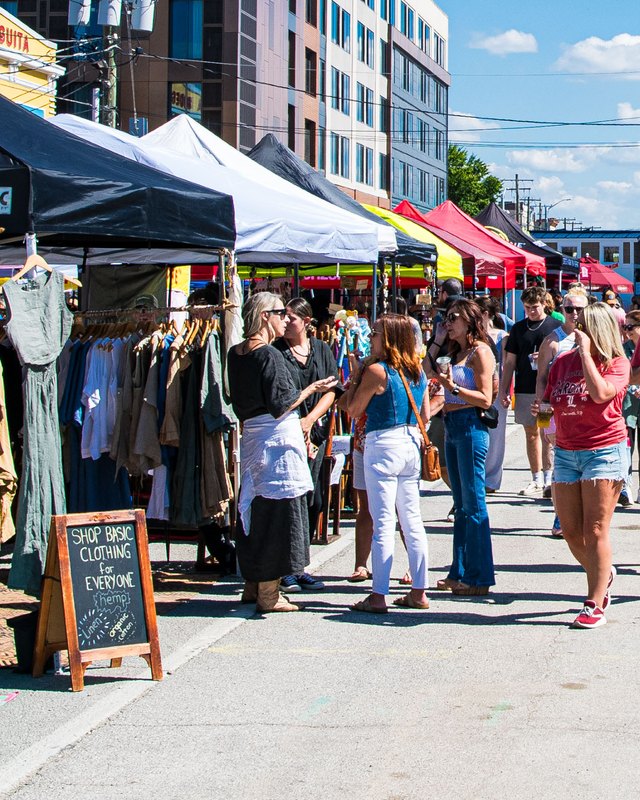 Shoppers browsing clothing racks and tents at an outdoor street market during NuLu Fest in Louisville.