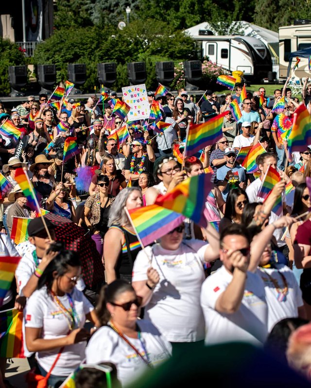 Crowd of marchers waving rainbow flags at the Boise Pride Festival parade