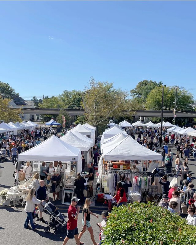 Crowds browsing white booth tents at an outdoor Clover Market street fair in Collingswood.
