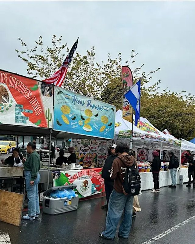 Food vendor booths and shoppers along a street at the Fordham Road Fair.