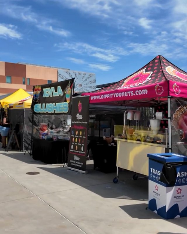 Vendor booths with canopies and food under a blue sky at Compton Fest