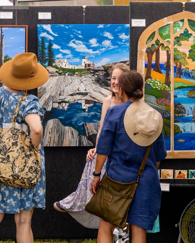 Visitors in hats viewing colorful paintings displayed on panels at the Pearland Grand Arts & Eats festival.