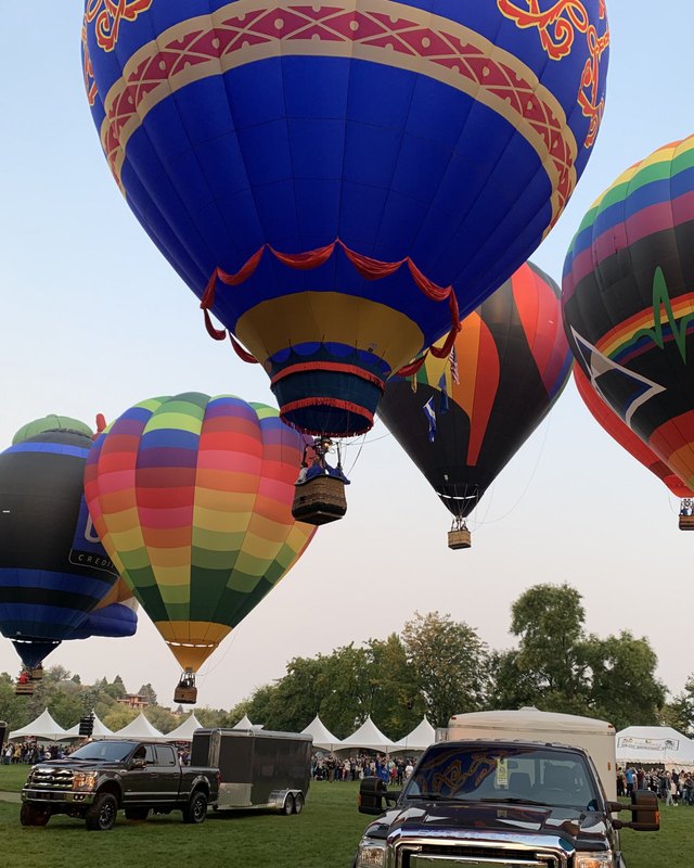Colorful hot air balloons inflating over a field with a crowd and vendor tents at the Spirit of Boise Balloon Classic