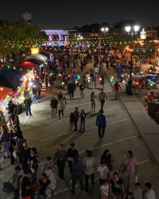 Evening night market with rows of vendor booths and shoppers crowding a town street