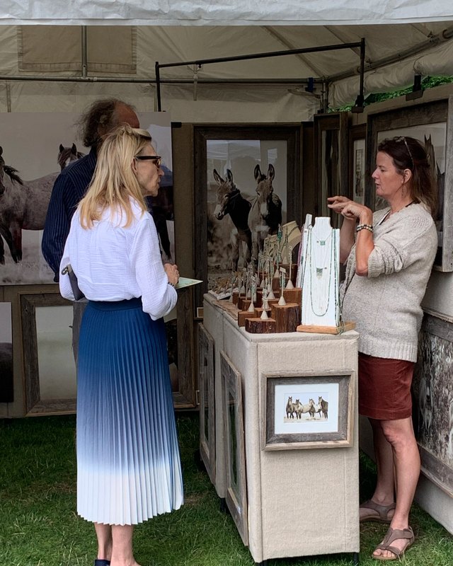 Visitors talking with an artist at a framed-art booth at the Ridgefield outdoor festival.