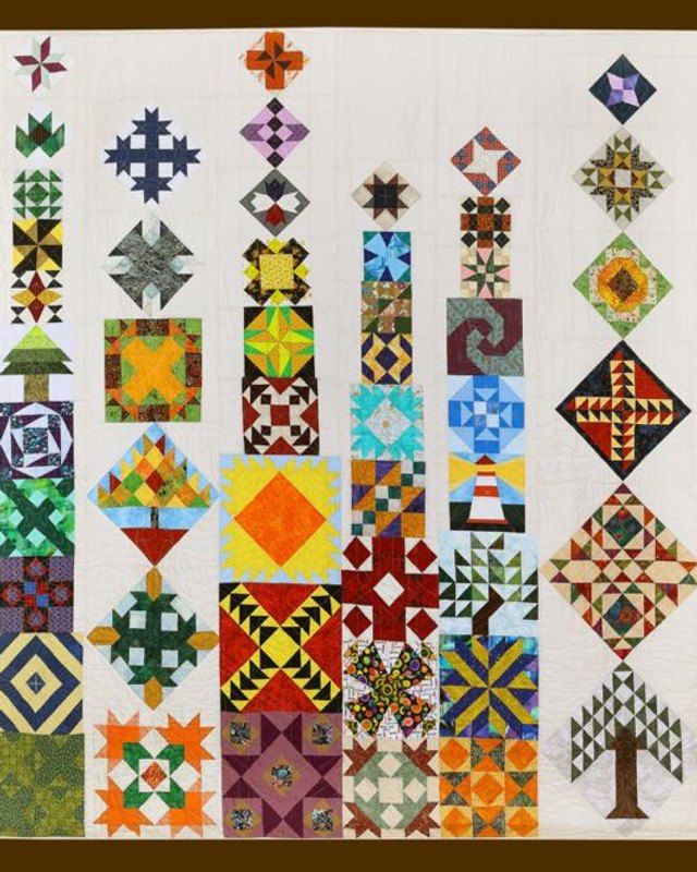 Colorful patchwork quilt with geometric blocks and a tree motif, shown at the Boise Basin Quilt Show.