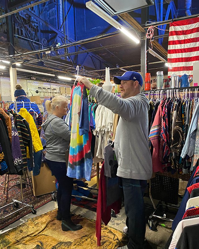 Shoppers browsing hanging vintage clothing racks inside the Fleur de Flea indoor market