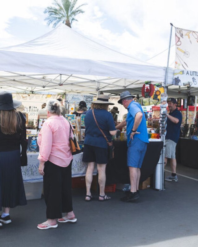 Shoppers browsing white-tent market booths at the Street Fair in Palm Desert.