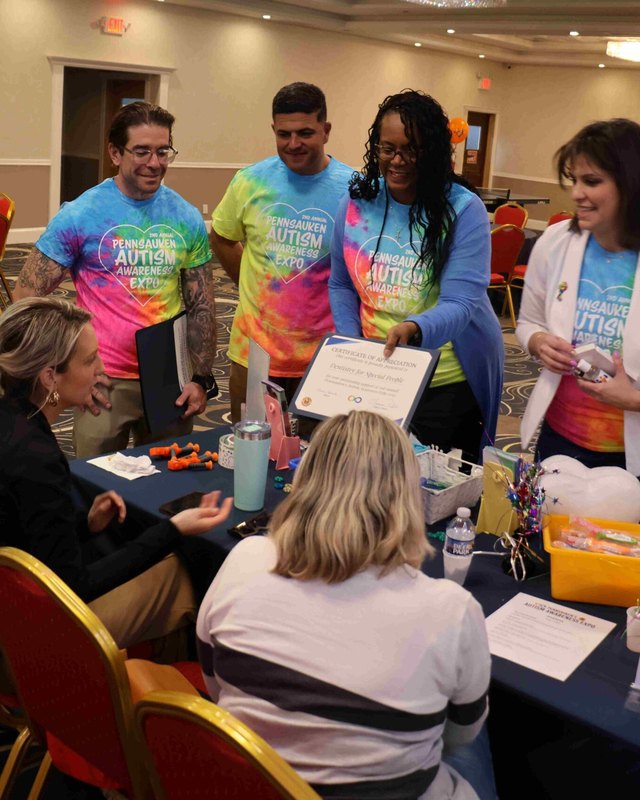 Volunteers and attendees at tables with a dentistry for special people sign, at a past Pennsauken Autism Awareness Expo.