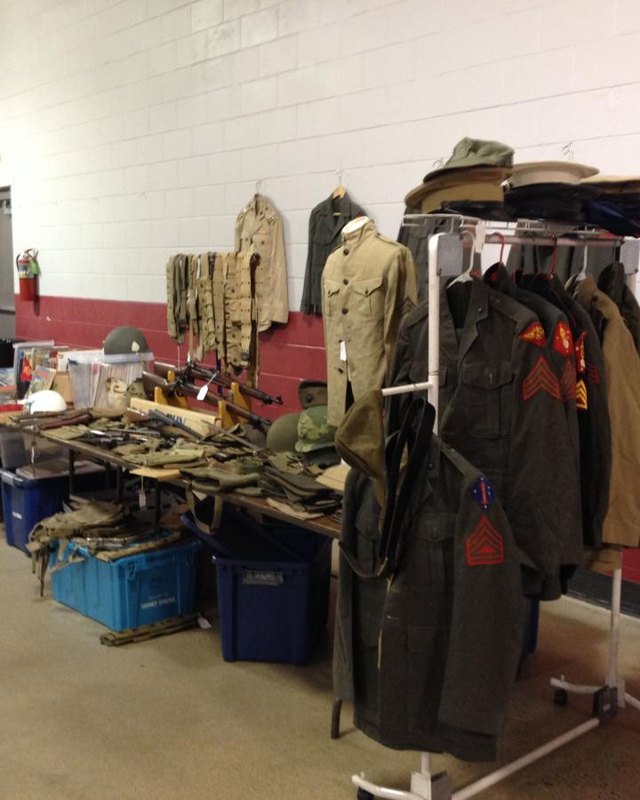 Vintage military clothing and gear laid out on tables and racks at an indoor antique sale