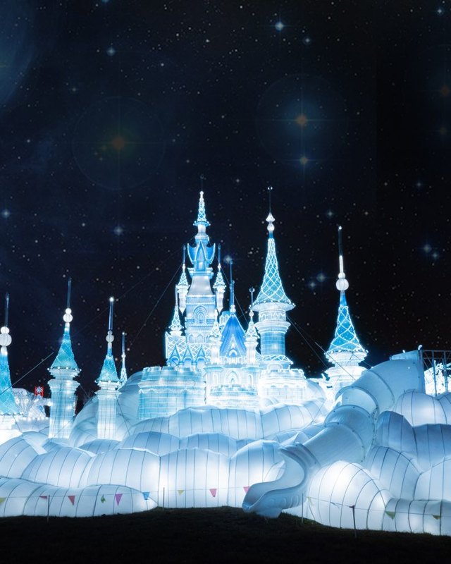 Illuminated ice castle sculpture glowing blue against a night sky at the LuminoCity festival.