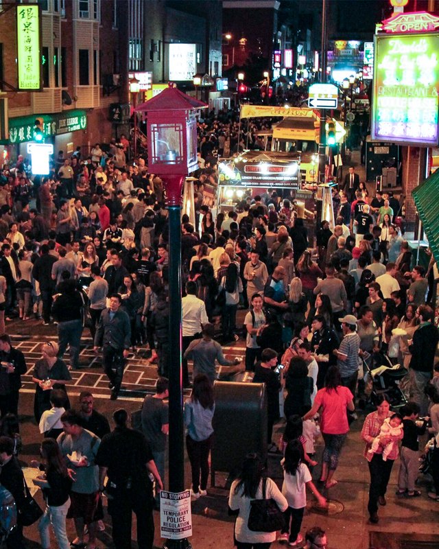 Dense night crowd of shoppers and visitors on a lit Chinatown street during the YèShì Chinatown Night Market.