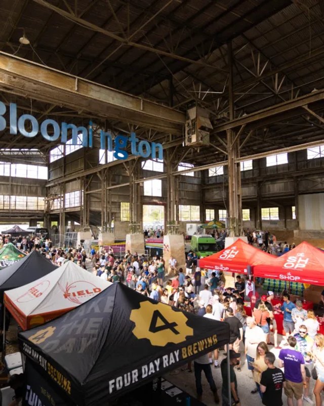 Crowd browsing tents and booths inside the high-ceilinged Woolery Mill hall during Spring Fest