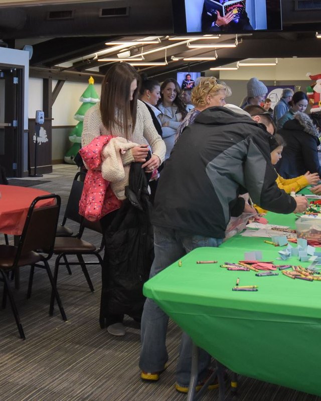 Attendees gathered at activity tables with green tablecloths at a Homer for the Holidays event.